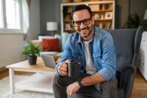 a man is sitting in a chair holding a cup of coffee .