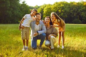 Smiling family of four in a sunny park.