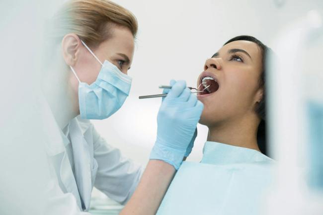 a female dentist is examining a woman 's teeth in a dental office .