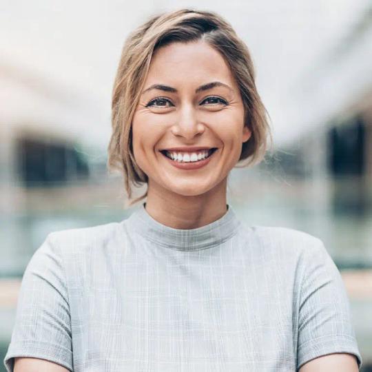 a woman is smiling for the camera with her arms crossed .