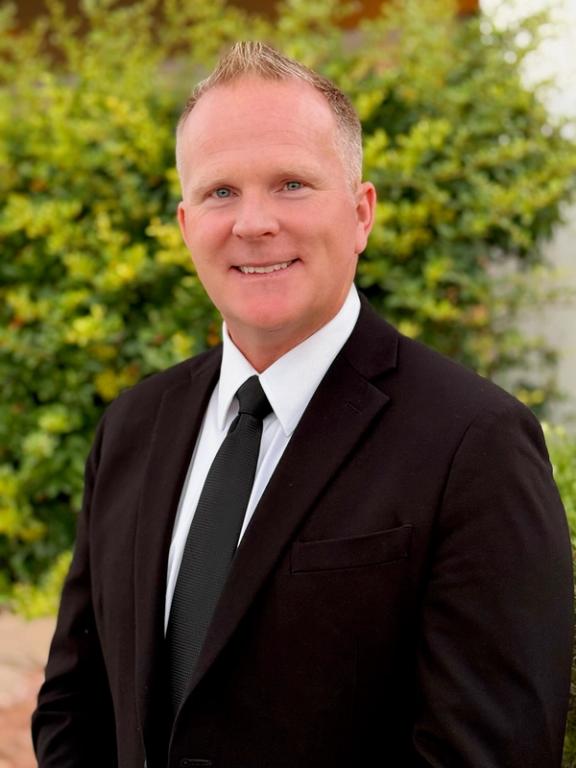 a man in a suit and tie is smiling for the camera .