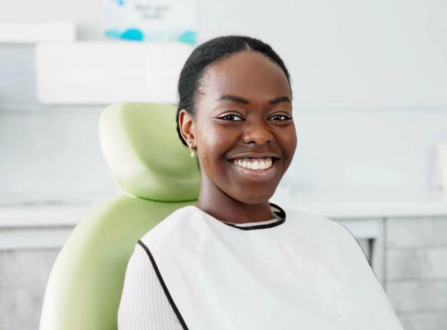 a woman is smiling while sitting in a dental chair .