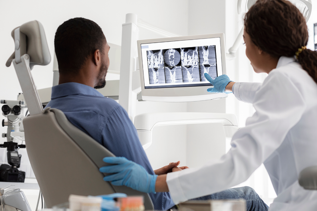 a dentist is showing a patient an x-ray of his teeth