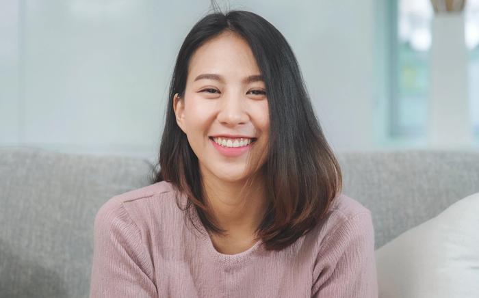 a woman is sitting on a couch smiling at the camera .