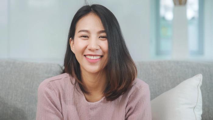 a woman is sitting on a couch smiling at the camera .