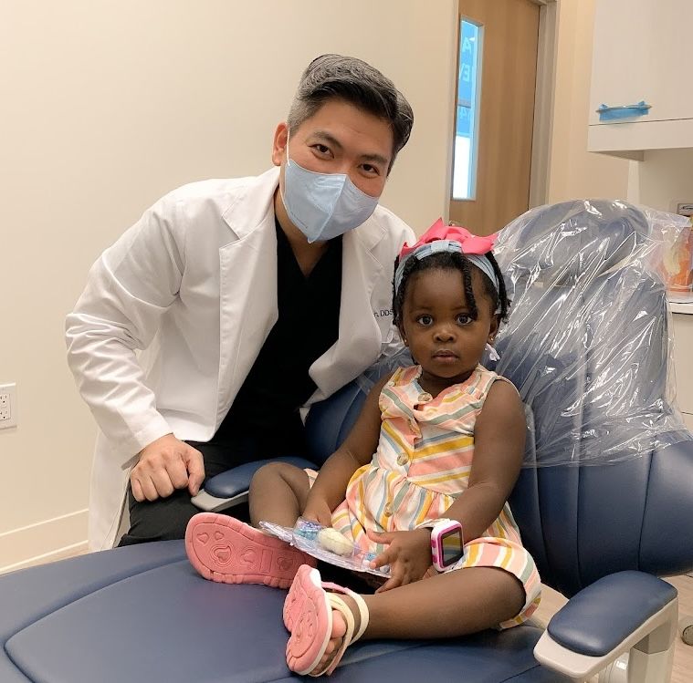 a little girl is sitting in a dental chair with a toothbrush in her hand .