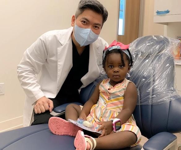 a little girl is sitting in a dental chair with a toothbrush in her hand .