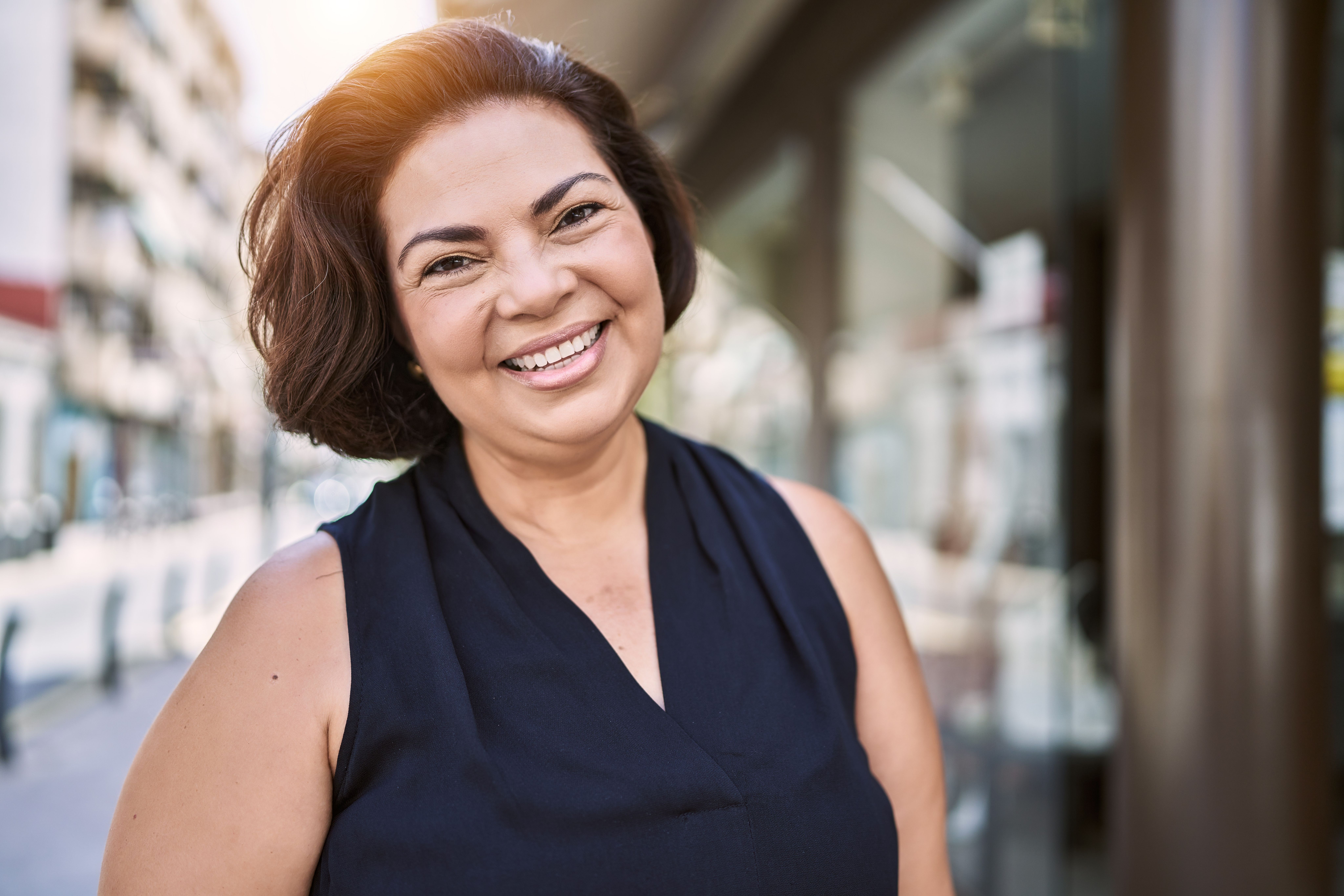 a woman is smiling for the camera while standing on a city street .