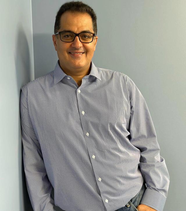 a man wearing glasses and a striped shirt is leaning against a wall .
