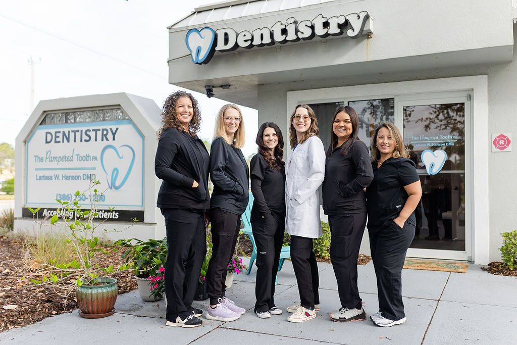 a group of women are posing for a picture in front of a dentistry office .