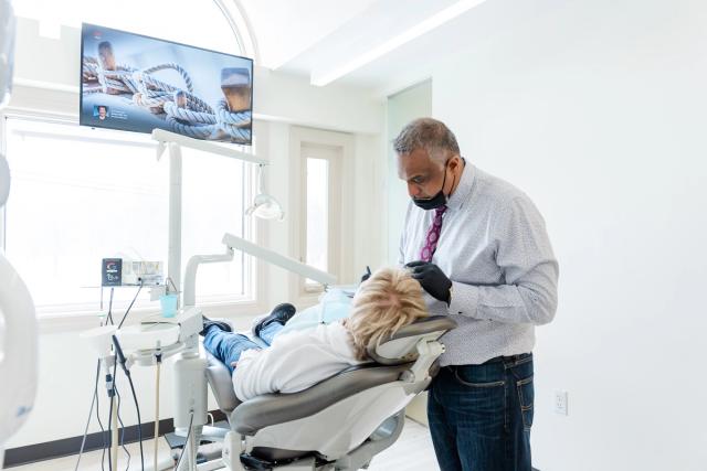 a dentist is examining a patient 's teeth in a dental office .