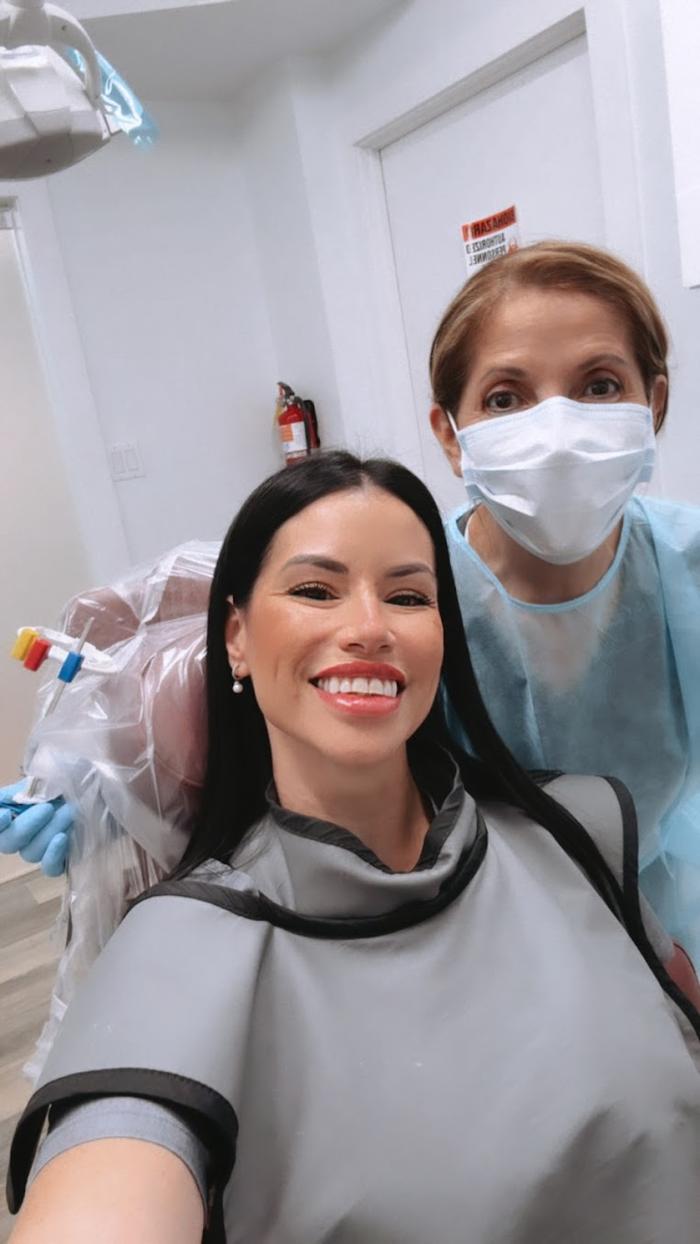 a woman in a dental chair next to a nurse wearing a mask