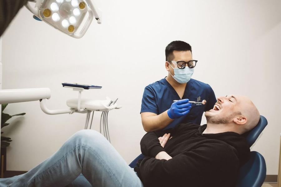 a man is sitting in a dental chair while a dentist examines his teeth .