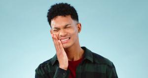 a young man is holding his face in pain because of a toothache .