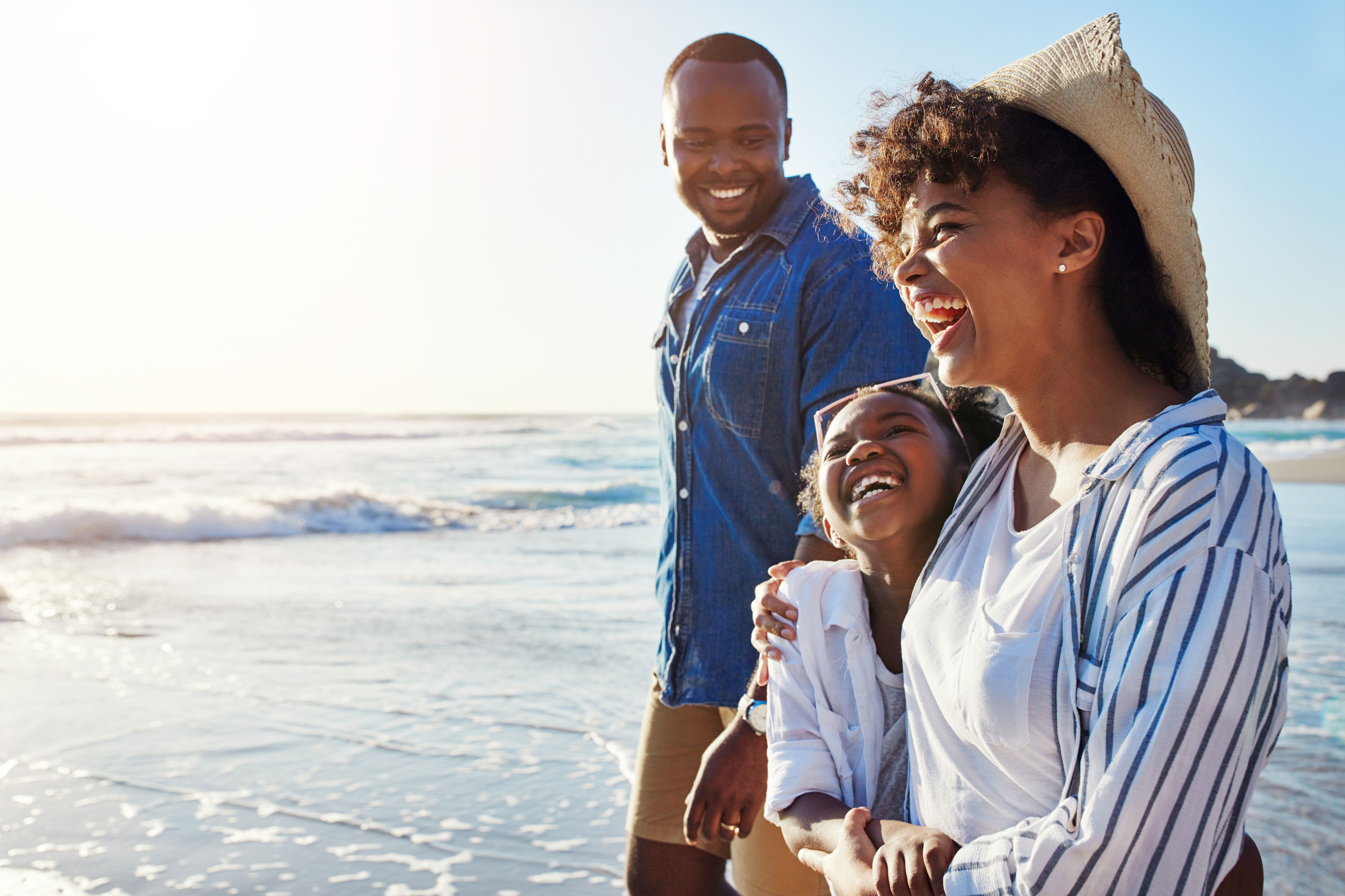 a family is walking on the beach and laughing .