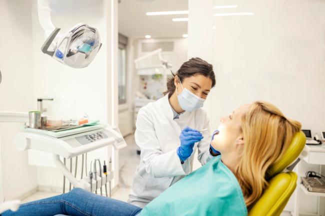 a woman is sitting in a dental chair while a dentist examines her teeth .