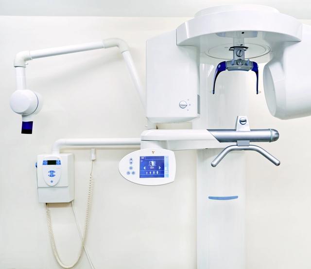 an x-ray machine is hanging from the ceiling in a dental office .