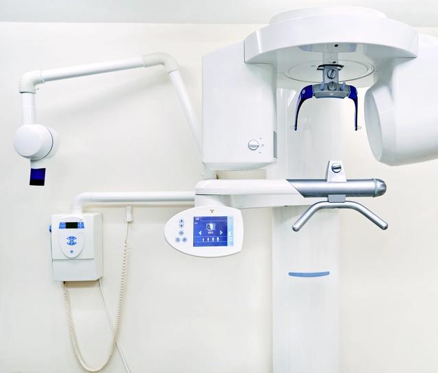 an x-ray machine is hanging from the ceiling in a dental office .