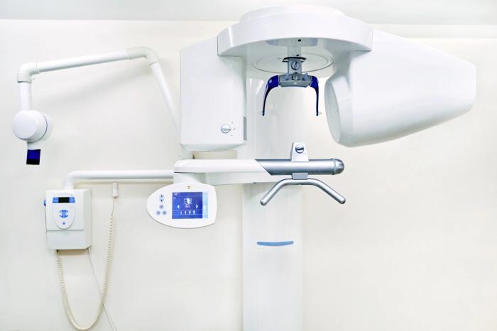 an x-ray machine is hanging from the ceiling in a dental office .