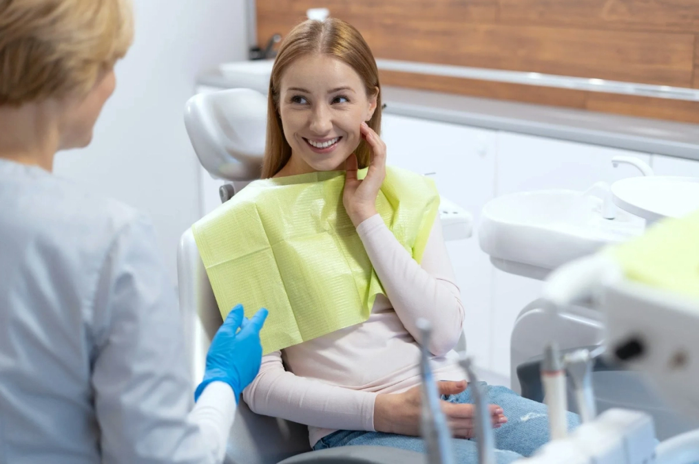 a woman is sitting in a dental chair and smiling