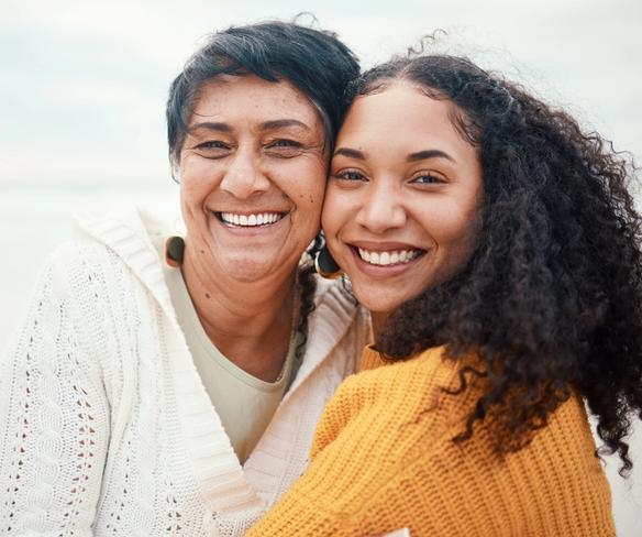 an older woman and a younger woman are posing for a picture on the beach .