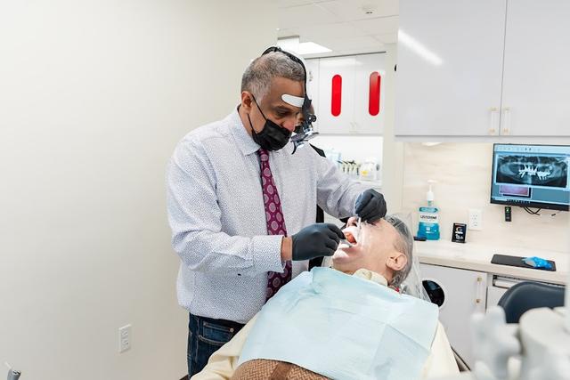 a dentist is examining a patient 's teeth in a dental office .