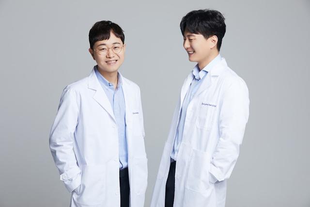 two doctors in white coats are standing next to each other and smiling .