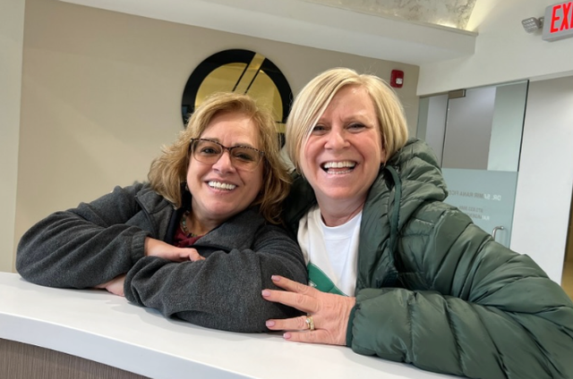 two women are posing for a picture in front of an exit sign