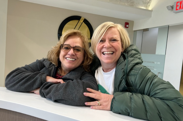 two women are posing for a picture in front of an exit sign