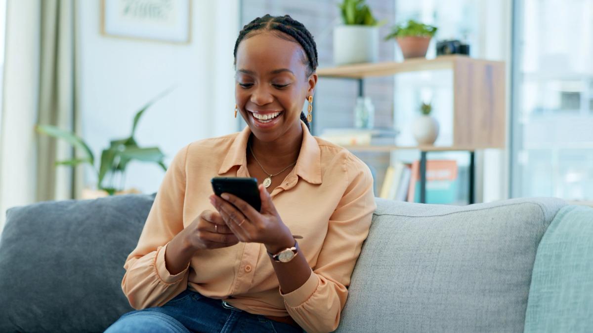 a woman is sitting on a couch looking at her cell phone .