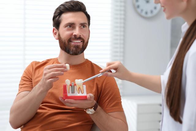 a man is holding a model of his teeth while talking to a dentist .