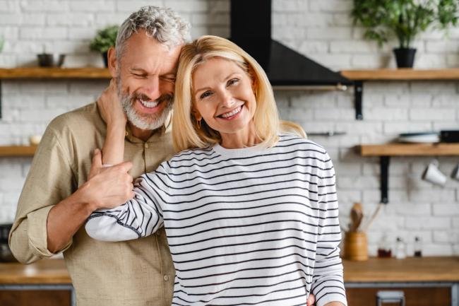 a man and a woman are posing for a picture in a kitchen .
