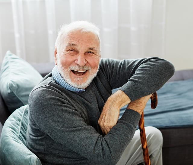 a smiling woman is sitting at a table with her hand on her chin .