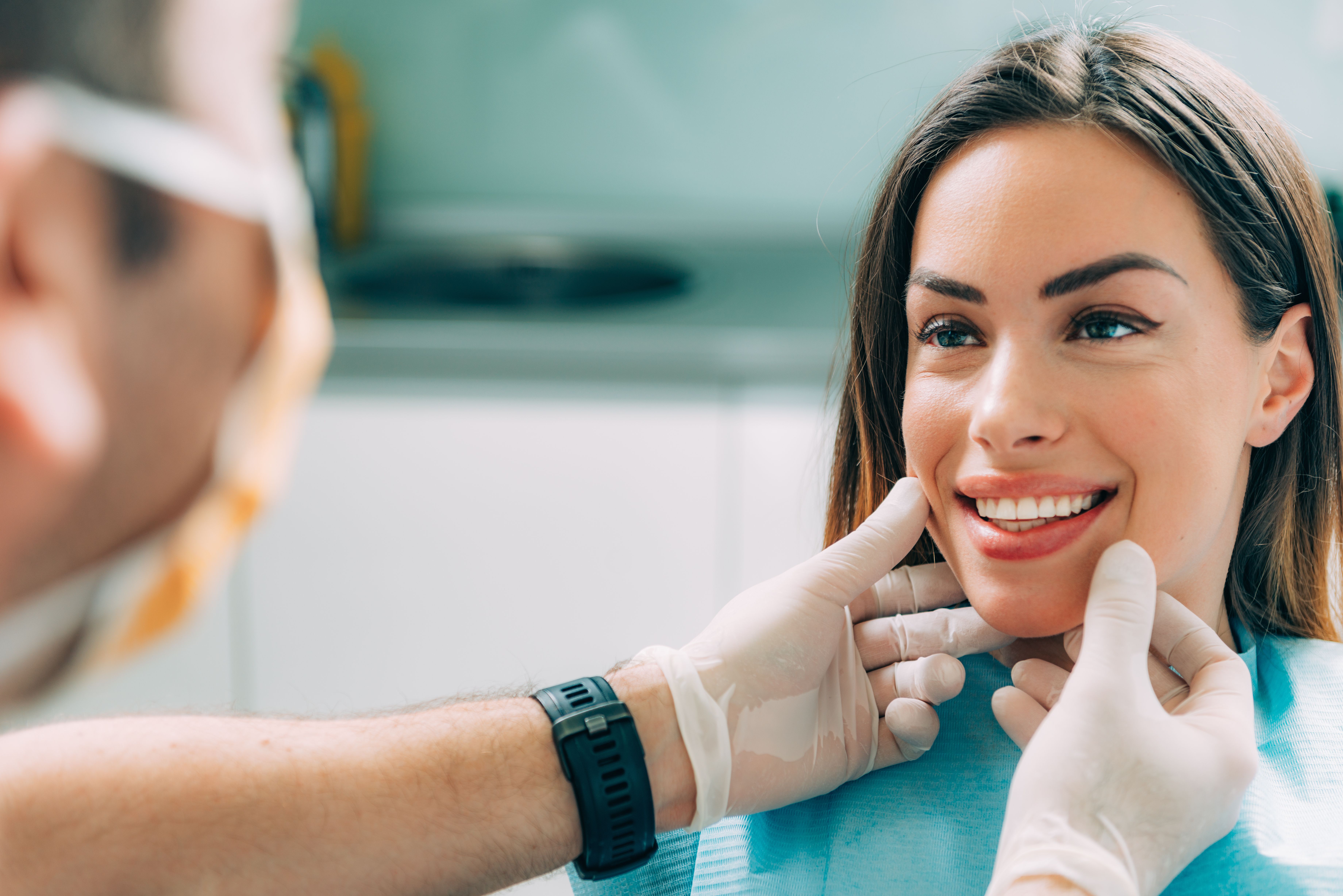 a woman is sitting in a dental chair while a dentist examines her teeth .
