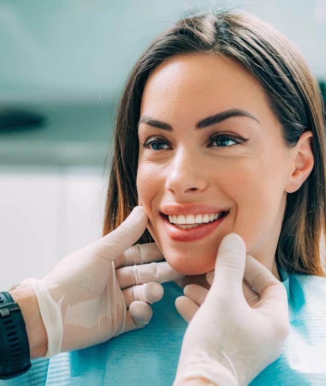 a woman is sitting in a dental chair while a dentist examines her teeth .