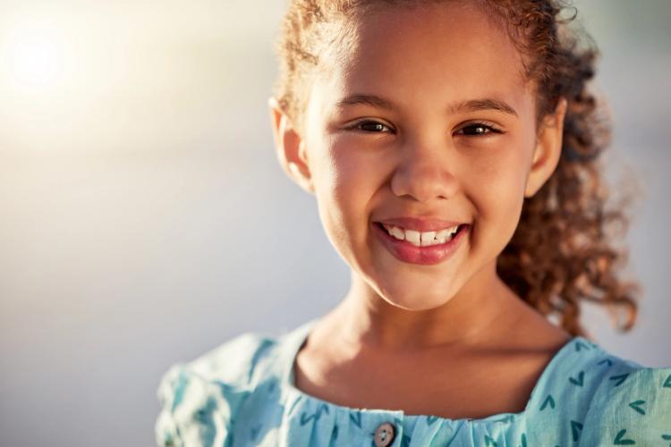 a little girl is smiling for the camera while wearing a blue dress .