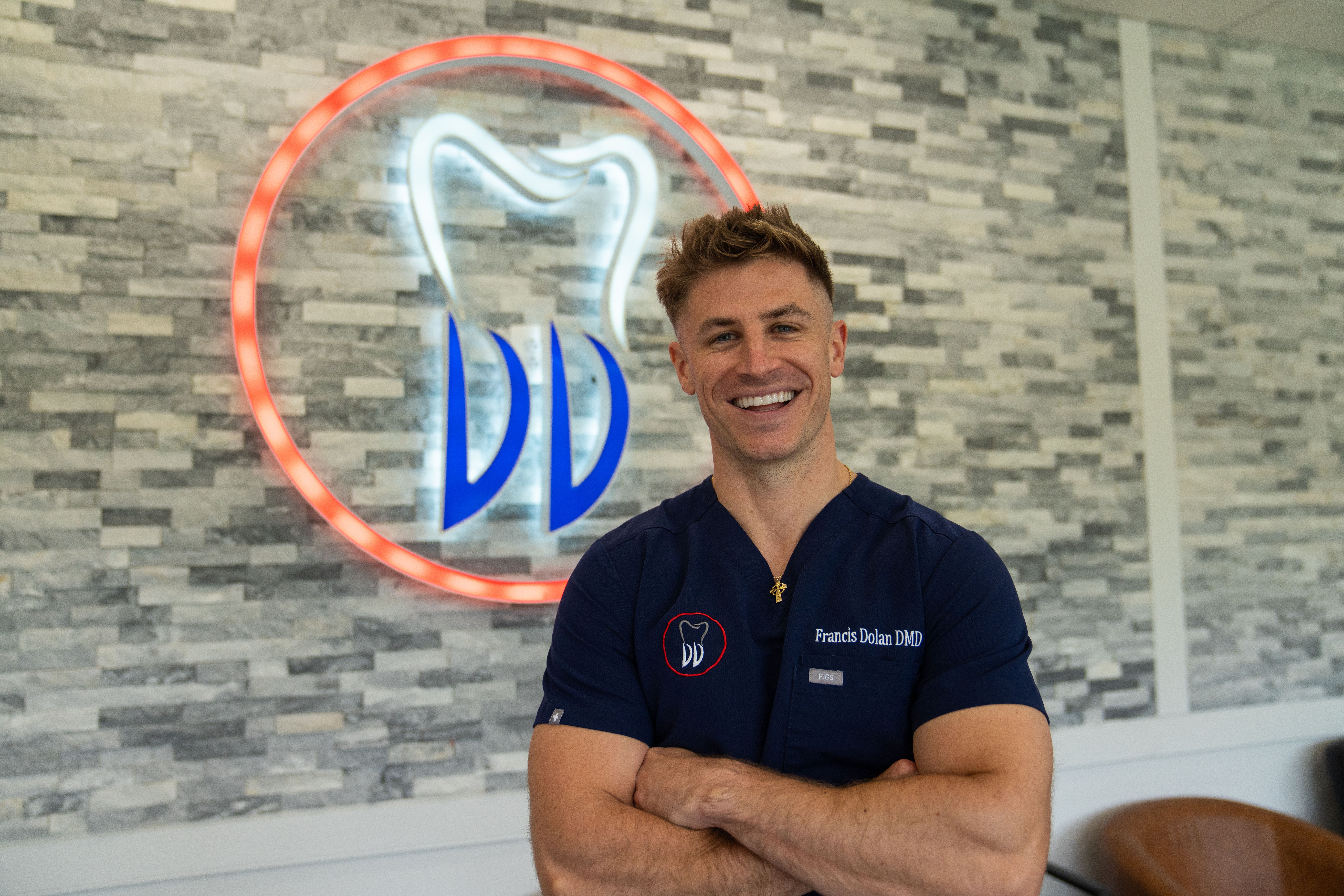a dentist is smiling in front of a dental sign .