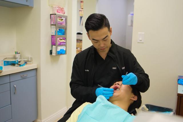 a dentist is examining a patient 's teeth in a dental office .