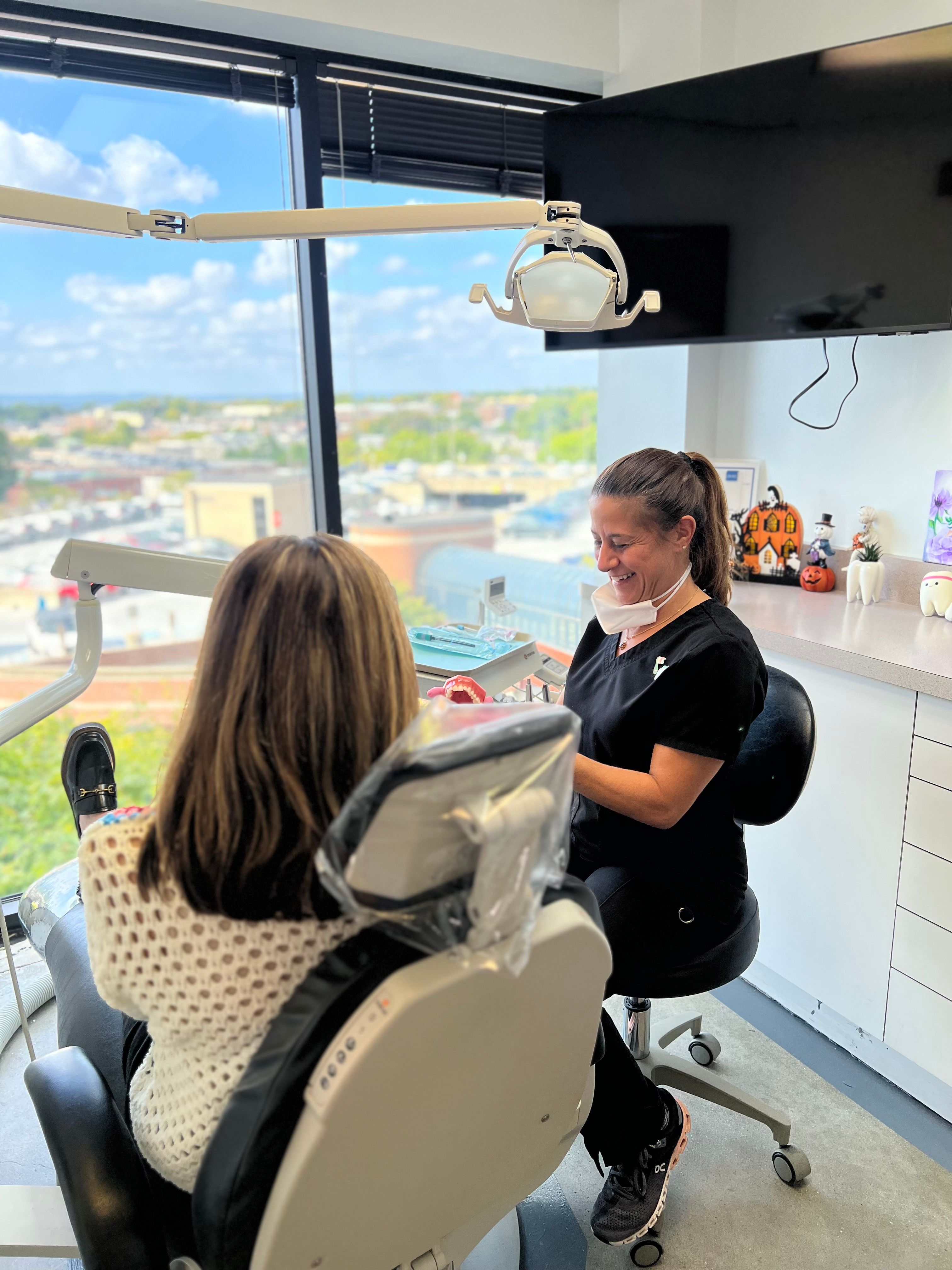 a woman is sitting in a dental chair talking to a dentist .