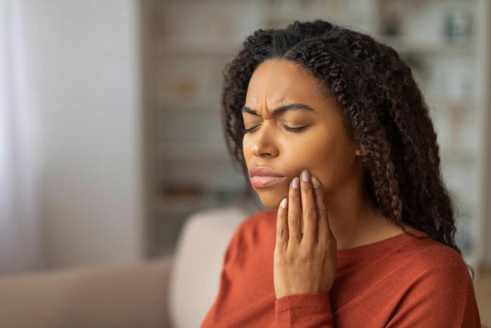 a woman is holding her face in pain because of a toothache .