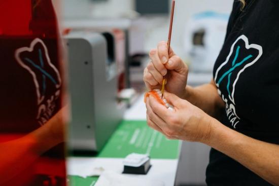 a woman is painting a tooth with a brush in a dental office .