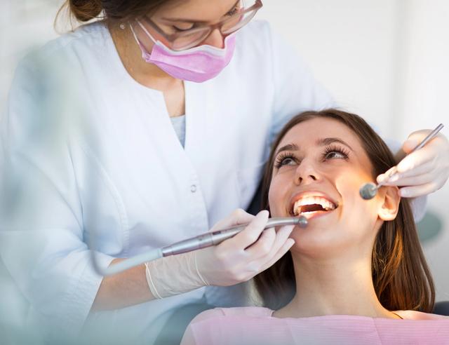 a woman is getting her teeth examined by a dentist .
