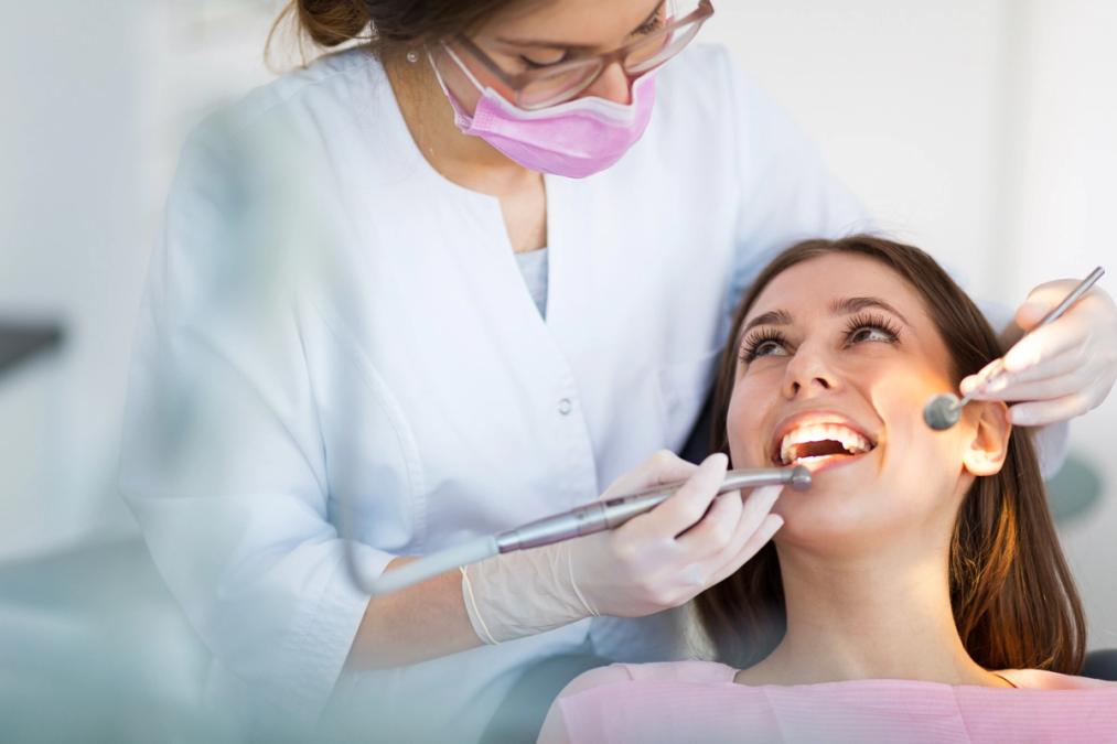 a woman is getting her teeth examined by a dentist.