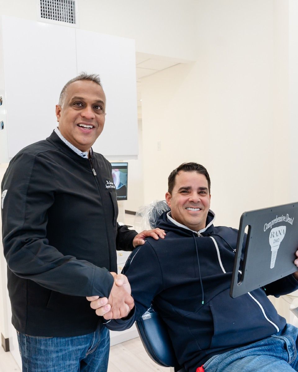a man sitting in a dental chair shaking hands with a dentist
