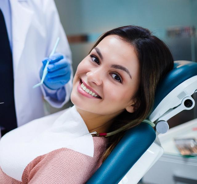 a woman is sitting in a dental chair while a dentist examines her teeth .