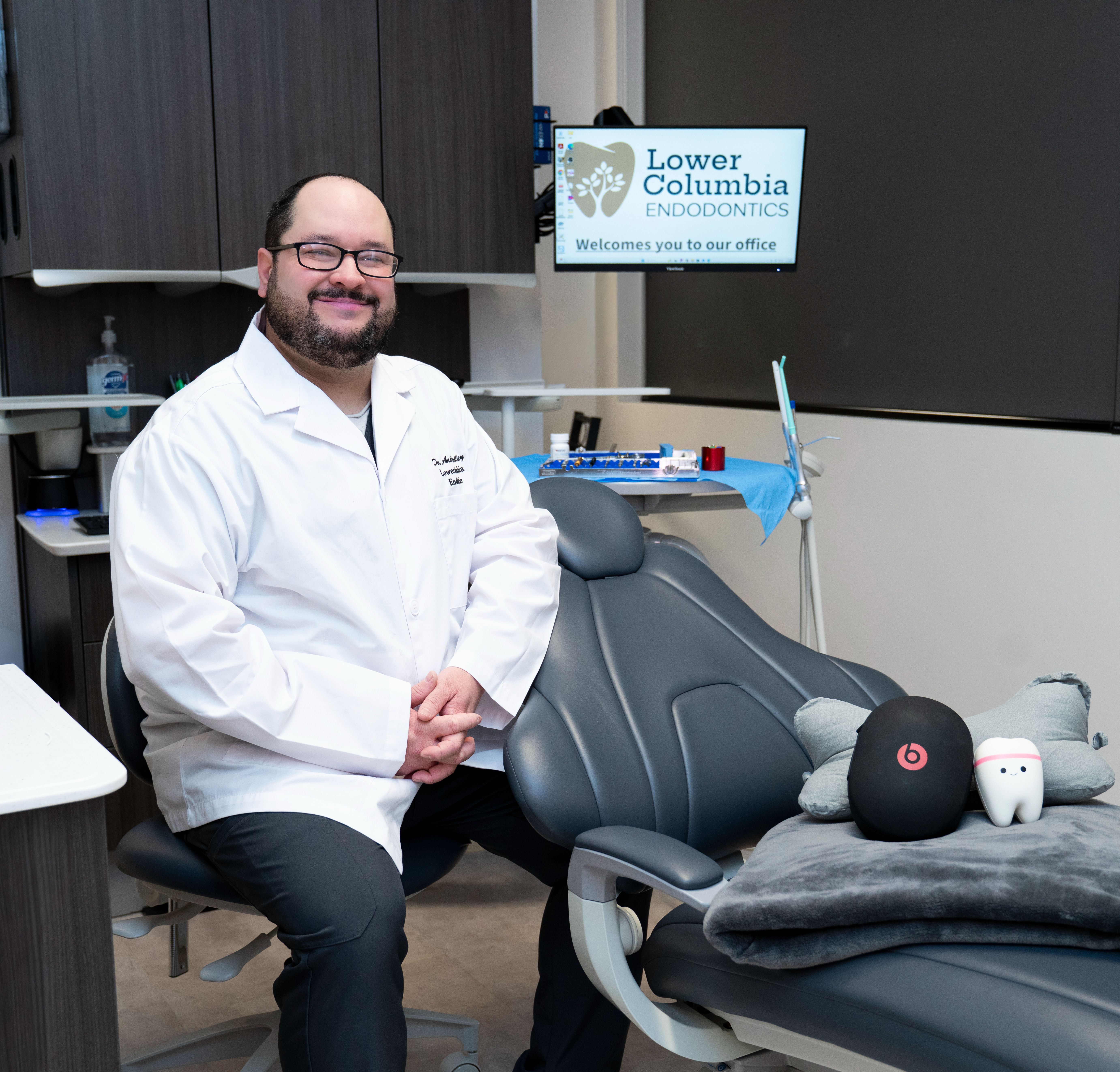 Dr. Andres Lopez smiles in a white lab coat and glasses.