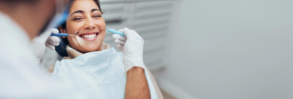 a woman is smiling while having her teeth examined by a dentist .