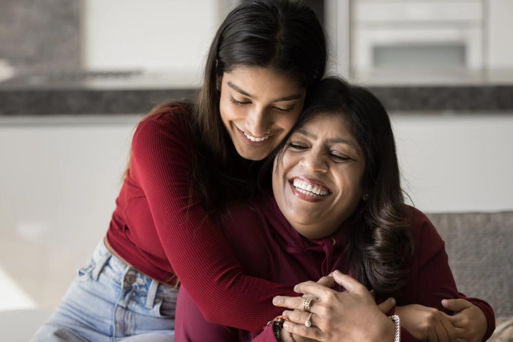 a young woman is hugging her mother on a couch .