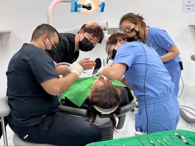 a group of dentists are working on a patient in a dental office .