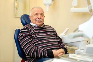 Elderly man smiling in a dental chair.